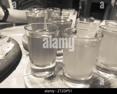 Ein Set von vielen köstlichen Schwarz-weiß-Gläsern, Schüsse mit starkem Alkohol, Wodka, Füllung, Brandy auf Holzständern auf einem Tisch in einem Café, Bar, Ruhe Stockfoto