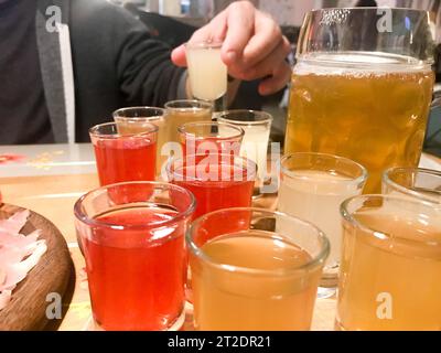 Eine Reihe von leckeren gelben orange roten Gläsern, Schüsse mit starkem Alkohol, Wodka, Brandy, Brandy, Bier auf Holzständern auf einem Tisch in einem Café, BA Stockfoto