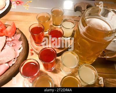 Fleischjause mit Alkohol aus Fleisch, Schinken, Basturma mit Soße und vielen Gläsern, Schüsse mit starkem Alkohol, Wodka, Füllung auf Holzständern auf einem Tablett Stockfoto