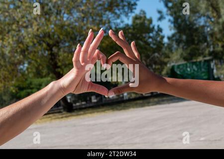 Hände verschiedener Ethnien, afrikanisch und europäisch, bilden mit ihren Fingern ein Herz. Vorstellung von Liebe, Freundschaft, Gleichheit Stockfoto
