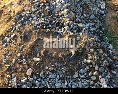 Steine liegen auf dem Boden in schwarzem Boden. Viele große Steine stapeln sich. Bau neuer Anlagen. Die Baumeister haben die Steine und den Boden in einem BI zusammengestellt Stockfoto