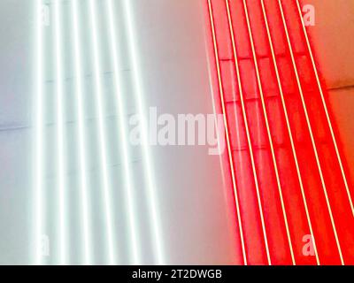 Neonstreifen, Beleuchtung an der U-Bahn-Station. Rote und weiße Streifen an einer schwarzen Decke. Helle Neonfarben, dekorative Panels. Stockfoto