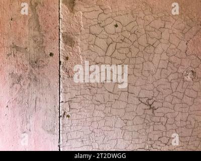 Textur. Rosafarbene Farbe gerissen. Strukturierte Farben, Wohnkultur, Inneneinrichtung. Schäden an der Wand, Schmutz, runde Löcher. Altes Metallblech in rosa Farbe. Babybett Stockfoto