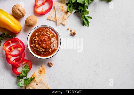 Walnuss und gebratener Paprika Dip Muhammara mit Pita und rotem Pfeffer auf weißem Hintergrund, Kopierraum. Arabisch gesundes veganes Essen. Nahöstliche Küche. Stockfoto