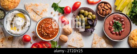 Auswahl an arabischen Mezze-Speisen - foul, Labneh-Joghurt, Muhamara-Dip auf weißem Hintergrund, Blick von oben, Banner. Nahöstliche Küche. Stockfoto
