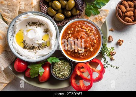 Auswahl an arabischen Mezze-Tellern - Labneh-Joghurt, Muhammara-Dip mit Pitabrot, Zaatar, Oliven und Gemüse. Nahöstliche Küche. Stockfoto