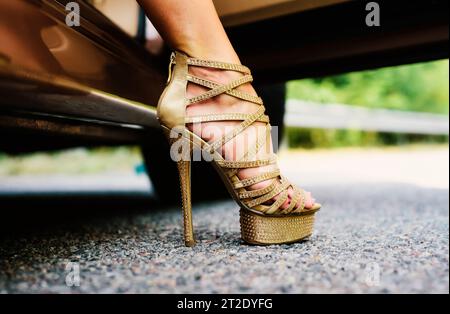 Damen Beine in High Heels. Luxuriöser urbaner Hintergrund. Die Frau trägt Schuhe auf High Heels. Nahaufnahme der weiblichen Beine. Frauenbeine in High-Heel-Gold Stockfoto