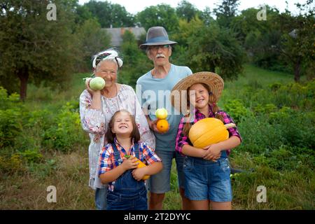 Glückliches Seniorenpaar, Oma und Opa mit Enkeln, die Gemüse ernten. Bauern orgäische Nahrung. Glückliches Familienleben Stockfoto