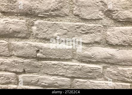 Dekorziegel für Wandverkleidung, Textur. Weiße Fliesenziegel, Stuckziegel, kleine Ziegelsteine für die Wandverkleidung. Stucksteine aus Zementmaterial. Stockfoto