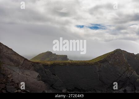 Eine Einzelfigur steht an einem stürmischen Tag auf einer Klippe nahe dem Hartland Quay, an der zerklüfteten Küste im Norden von Devon, Großbritannien Stockfoto