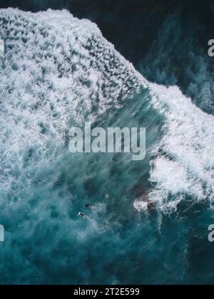 Drohnenaufnahme von zwei Surfern, die auf Teneriffa auf den Kanarischen Inseln im starken blauen Meer paddeln Stockfoto