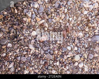Textur, Hintergrund, kleine Steine. Heißes, tropisches Land mit Meer und Bergen. Kieselsteine und kleine Steine am Strand. Stockfoto