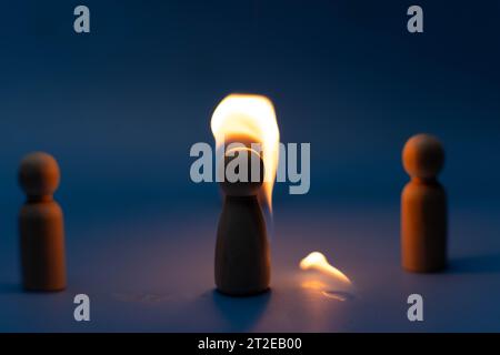 Die Holzfigur, isoliert von der Menge durch ein Feuer, wird wegen Verwirrung und Konflikten mit anderen vertrieben. Konzepte von Dissens, Ablehnung, d Stockfoto