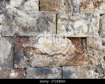 Eine alte Steinmauer aus Steinen und gehauenen Blöcken. Stockfoto