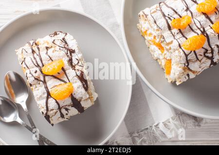 Schwedische Budapester Brötchen mit Haselnussmeringue und Mandarinen in Nahaufnahme auf dem Teller auf dem Tisch. Horizontale Draufsicht von oben Stockfoto