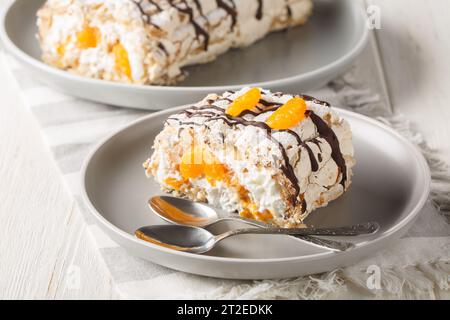 Köstliches hausgemachtes schwedisches Dessert Budapest Rollkuchen gefüllt mit Schlagsahne und Mandarinen in Nahaufnahme auf einem Teller auf dem Tisch. Horizontal Stockfoto