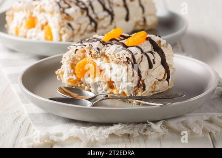 Schwedische Budapester Brötchen mit Haselnussmeringue und Mandarinen in Nahaufnahme auf dem Teller auf dem Tisch. Horizontal Stockfoto