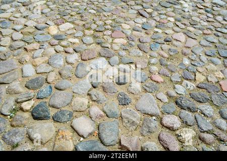 Die Textur der Steinstraße, Pflaster, Wände aus großen grauen alten mittelalterlichen runden starken Steinen, Kopfsteinpflaster. Der Hintergrund. Stockfoto