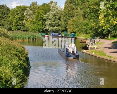 Ein Mann und eine Frau an Bord eines Schmalbootes, der auf dem Trent and Mersey Canal im ruhigen, ländlichen Cheshire fährt. An einem sonnigen Tag im Sommer. Stockfoto