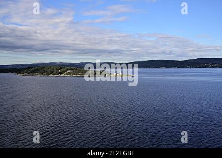 Weitwinkelblick auf den Oslofjord mit Wäldern und Berglandschaften an der Küste, mit Søndre Langåra-Nebelglocke auf der Insel Langåra, Norwegen Stockfoto