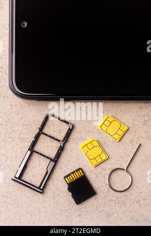 Smartphone und freie Steckplätze für Nano-SIM-Karten, zwei Nano-SIM-Karten, Micro-SD-Laufwerk und Metallschlüssel auf grauem Hintergrund Stockfoto