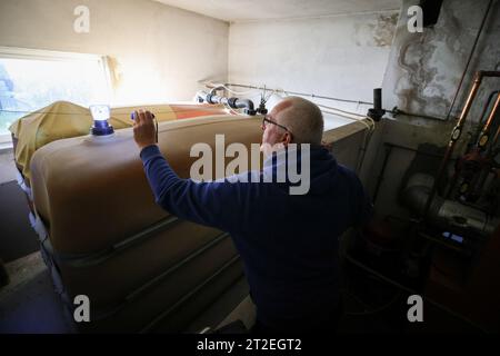 Bad Brahmstedt, Deutschland. Oktober 2023. Ein Mitarbeiter eines Diesel- und Heizölunternehmens überprüft den Füllstand in den Tanks, wenn Heizöl an einen Kunden in einem Einfamilienhaus geliefert wird. Quelle: Christian Charisius/dpa/Alamy Live News Stockfoto