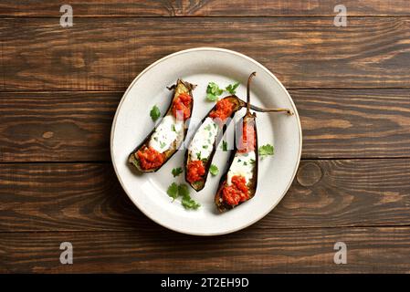 Geröstete Aubergine mit Joghurt und Tomatensauce Dressing auf hölzernem Hintergrund. Draufsicht, flach Stockfoto