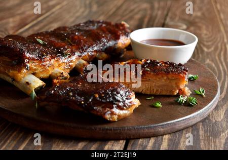 Nahaufnahme von Barbecue Schweinerippchen auf dem Schneidebrett über Holztisch. Stockfoto