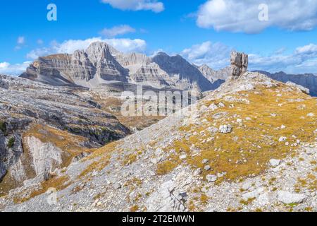 Großer freistehender Kalkstein gegen geschichtete Gebirgszüge in den Brenta-Dolomiten in Italien, Herbstsaison Stockfoto