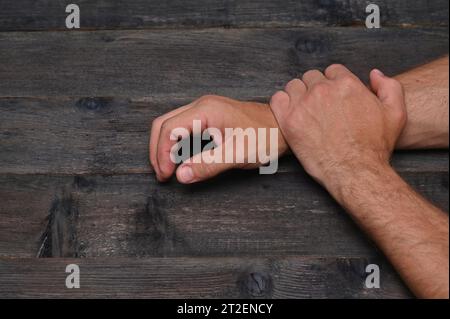 Die Hände des Mannes liegen auf einem Holztisch. Nahaufnahme Stockfoto