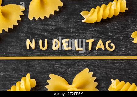 Augsburg, Bayern, Deutschland - 19. Oktober 2023: Nudeltageswort aus Buchstabennudeln zwischen verschiedenen Nudelsorten. Symbolbild Weltnudeltag am 25. Oktober *** Nudeltag Wort aus Buchstaben nudeln geformt inmitten von verschiedenen Nudel Sorten. Symbolbild Weltnudeltag am 25. Oktober Stockfoto
