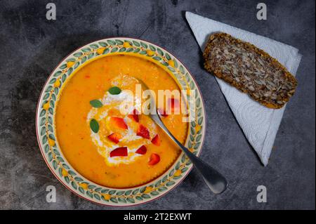 Eine warme Herbstmahlzeit mit Butternusskürbis-Suppe und einer Scheibe dunklem Brot. Stockfoto