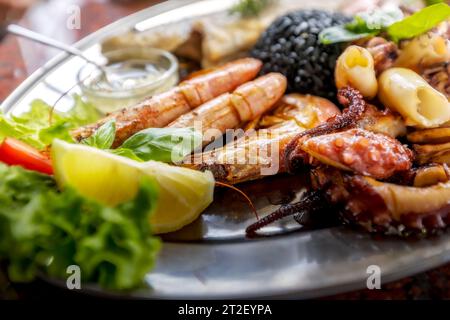 Gerösteter gemischter Fisch und Meeresfrüchte-Teller mit Calamari-Tintenfischen, Garnelen und gegrilltem Oktopus, mediterrane Küche Stockfoto