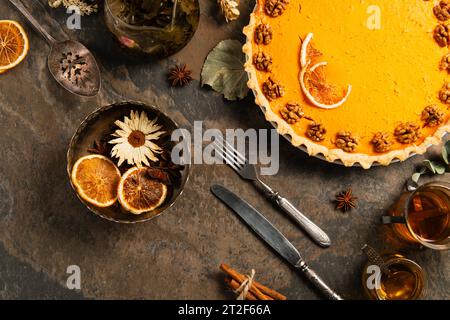 Kürbiskuchen mit Walnüssen und Orangenscheiben in der Nähe von Kräutern und Gewürzen, Thanksgiving-Komposition Stockfoto