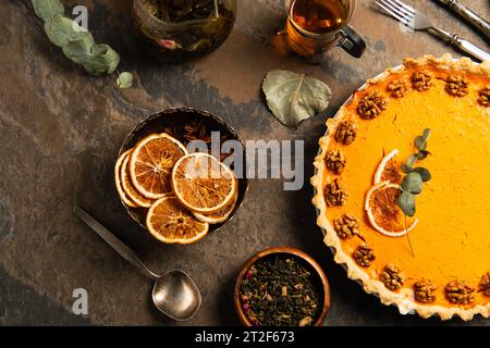 thanksgiving Stillleben, garniert Kürbiskuchen neben getrockneten Orangenscheiben und Gewürzen auf Steinoberfläche Stockfoto