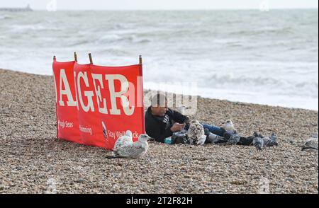 Brighton UK 19. Oktober 2023 - Besucher an einem windigen Tag entlang der Südküste von Brighton Beach, als Storm Babet Teile Großbritanniens mit roten Wetterwarnungen in Schottland überquert: Credit Simon Dack / Alamy Live News Stockfoto