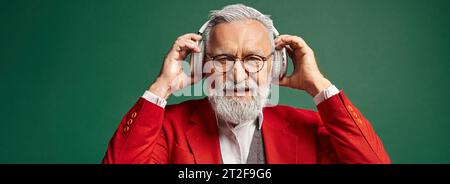 Stilvoller Weihnachtsmann mit Bart und Brille, Kopfhörer, Blick auf Kamera, Winter, Banner Stockfoto