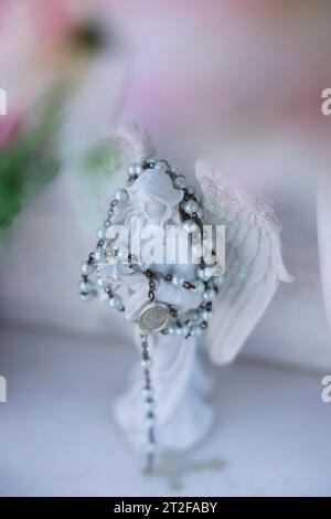 Kleine Engelsfigur, mit Rosenkranzkette an einem Urnengrab auf einem Friedhof gehängt, Bari Sardo, Ogliastra, Sardinien, Italien Stockfoto