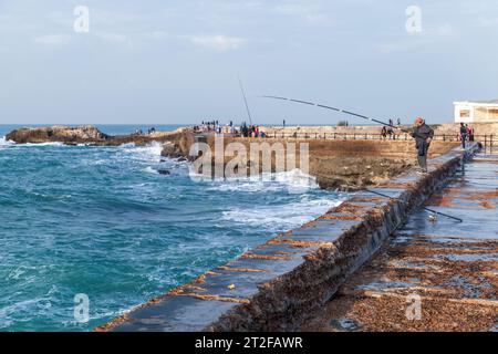 Alexandria, Ägypten - 13. Dezember 2018: Fischer mit Rute ist an einem stürmischen Tag auf dem nassen Pier Stockfoto