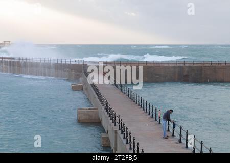 Alexandria, Ägypten - 19. Dezember 2018: Fischer mit Rute ist an einem stürmischen Tag auf einem Pier Stockfoto