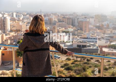 Ein junges Touristenmädchen, das die Stadt aus dem Blickwinkel des Cerro San Cristobal in der Stadt Almeria, Andalusien, betrachtet. Spanien. Costa del sol in der Stockfoto