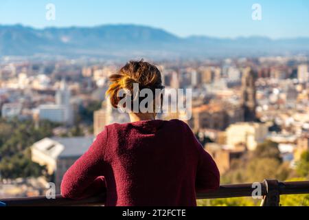 Eine junge Frau mit Blick auf die Stadt und die Kathedrale der Inkarnation von Malaga vom Castillo de Gibralfaro in der Stadt Malaga Stockfoto