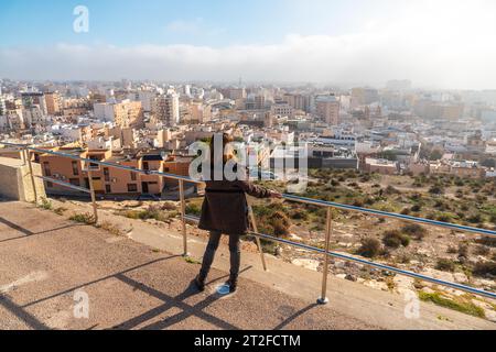 Ein junges Touristenmädchen, das die Stadt vom Aussichtspunkt Cerro San Cristobal in der Stadt Almeria, Andalusien, betrachtet. Spanien. Costa del sol in der Stockfoto