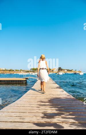 Eine junge Frau in einem Kleid in Cadaques, die auf einer Holzstege am Meer entlang läuft, Costa Brava von Katalonien, Gerona, Mittelmeer. Spanien Stockfoto