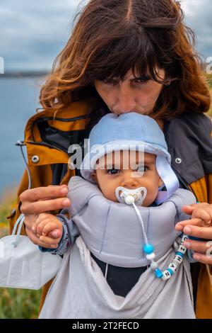 Eine junge Mutter mit ihrem Baby am Phare du Cap Frehel ist ein maritimer Leuchtturm in Cotes-dÂ´Armor Frankreich . An der Spitze von Cap Frehel Stockfoto