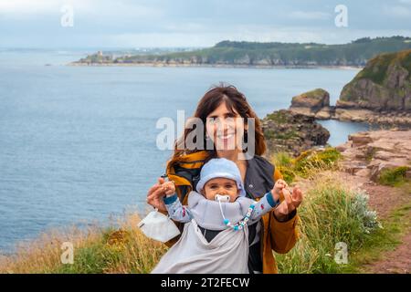 Eine junge Mutter mit ihrem Baby am Phare du Cap Frehel ist ein maritimer Leuchtturm in Cotes-dÂ´Armor Frankreich . An der Spitze von Cap Frehel Stockfoto