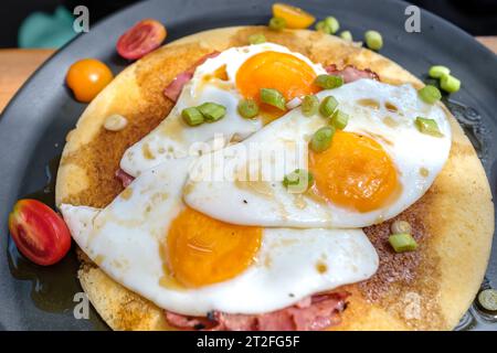 Blick auf Spiegeleier und Speck auf einem Pfannkuchen garniert mit Tomaten und Zwiebeln in iOS Griechenland Stockfoto