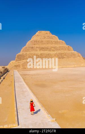 Eine junge Frau besucht die Stufenpyramide von Djoser, Sakkara. Ägypten. Die wichtigste Nekropole in Memphis. Die erste Pyramide der Welt Stockfoto