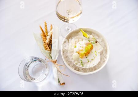 Jakobsmuschel in Soße mit fliegenden Fischkaviar auf einer Schale auf Eis in einem Restaurant. Hochwertige Fotos Stockfoto