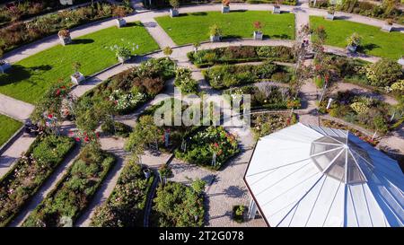 Beeindruckender Blickwinkel auf den Rosengarten des Botanischen Gartens Planten un Blomen. Leute (Popelgruppe), die auf grünem Gras sitzen: Entspannen, vielleicht essen Stockfoto